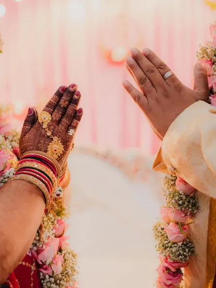A symbolic shot of the bride and groom's hands in a prayer position (namaste) during their wedding ceremony.