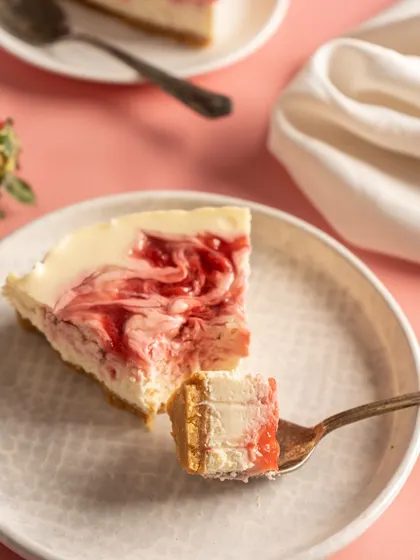 A perfect bite of my Baked Strawberry Cheesecake, showing the creamy texture and swirls of strawberry compote.