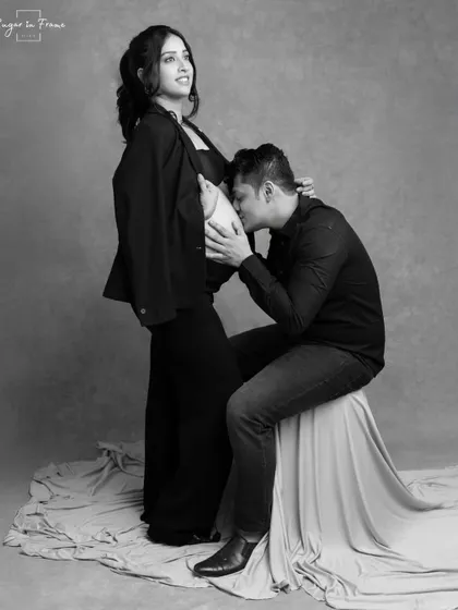 A tender and modern black and white portrait. The father-to-be gently kisses the baby bump, creating a timeless and intimate memory of this special time.