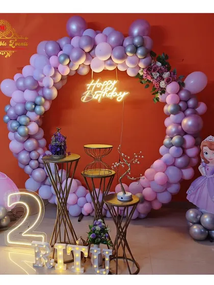 A lovely Sofia the First theme for a 2nd birthday, using a purple and pink color palette with princess cutouts and a neon 'Happy Birthday' sign.