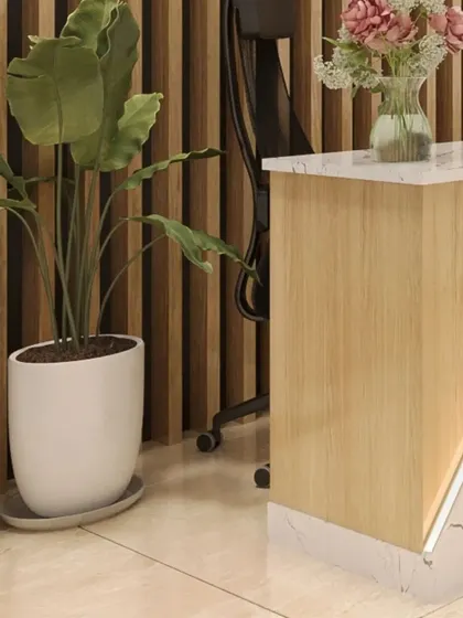 A close-up showing the material combination of light wood, marble, and biophilic elements like the large indoor plant, which contribute to a sustainable and healthy workspace design.