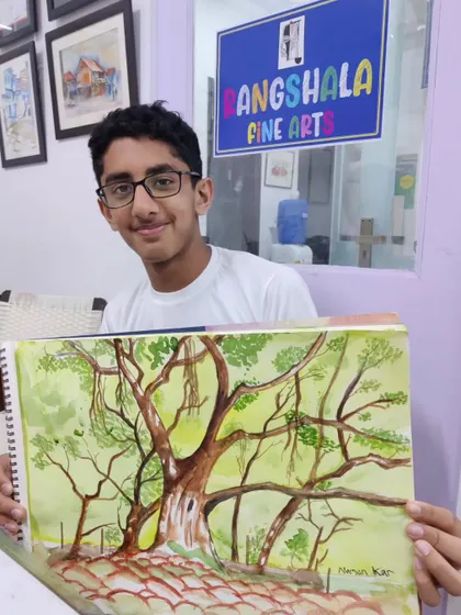 A student displays his finished watercolor painting of a large banyan tree, successfully capturing the complex network of branches and roots.
