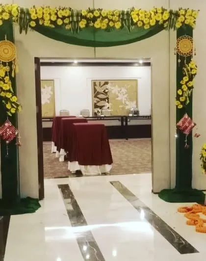 A simple and elegant entrance arch for an indoor event, decorated with green drapes and yellow flowers.