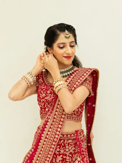 A candid moment of the bride getting ready for her reception. The pink eyeshadow and matching lip color create a harmonious and romantic look.