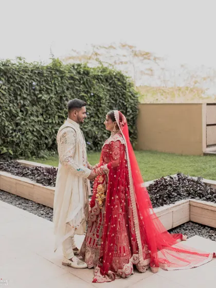 A classic wedding portrait with the couple holding hands against a backdrop of greenery.