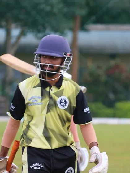 A batter walks onto the field, focused and prepared for his innings.