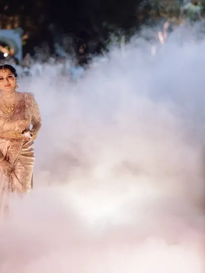 The bride making a dramatic and beautiful entrance through a cloud of smoke at her evening wedding.