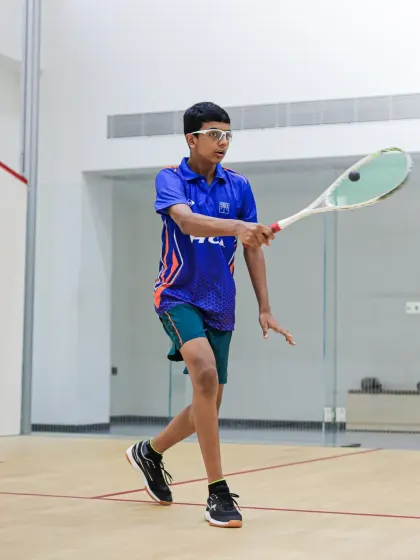 A full-body shot of Aryaman Singh in action on the squash court, displaying his athletic posture and readiness.