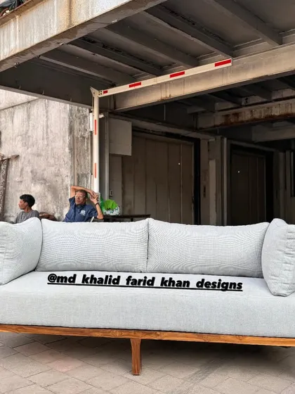 A front view of the light grey upholstered sofa with its unique cane-panelled back and armrests.
