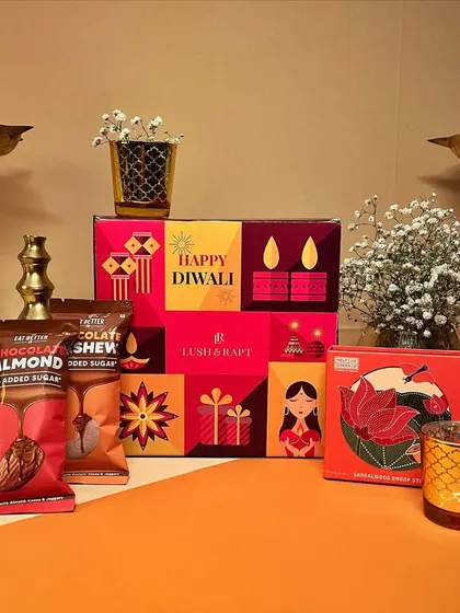 A festive flat-lay of one of our colorful Diwali boxes, complete with healthy snacks, a candle, and other treats.
