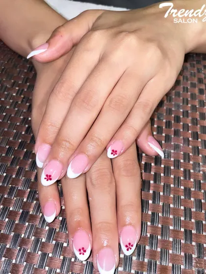 I love adding a personal touch to a classic design. Here, I've enhanced a traditional French manicure with a tiny, hand-painted red flower on the accent nail for a subtle pop of color and detail.