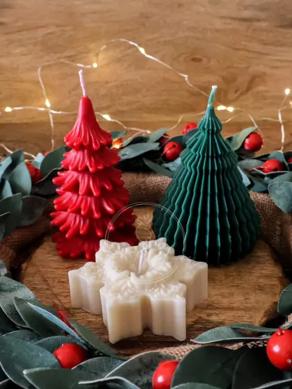 A festive trio of Christmas candles, featuring a red and green tree and a classic white snowflake.