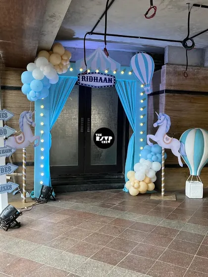 A whimsical carnival entrance with blue curtains, carousel unicorns, and a signpost pointing to games, food, and rides.