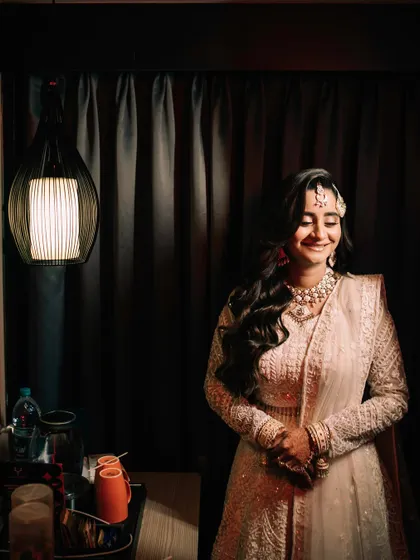 A candid shot of the bride smiling, captured in a softly lit room. This image feels natural and intimate, showcasing her happiness in a quiet moment.