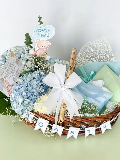 A sweet and gentle hamper for baby Agastya's second birthday. This basket features soft blue hydrangeas, a personalized name banner, and carefully wrapped gifts, creating a calm and loving theme.