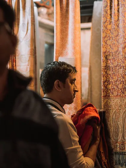 A customer inspecting a shawl at the Chatta Chowk market. The hanging textiles create beautiful layers and textures for a candid photograph.