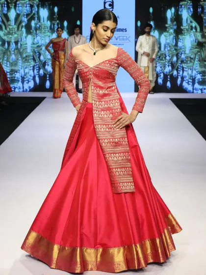 This outfit is a great example of fusion wear. I combined a traditional pink Banaras silk skirt with a modern, off-shoulder koti jacket featuring long, embroidered sleeves, creating a regal yet contemporary ensemble.