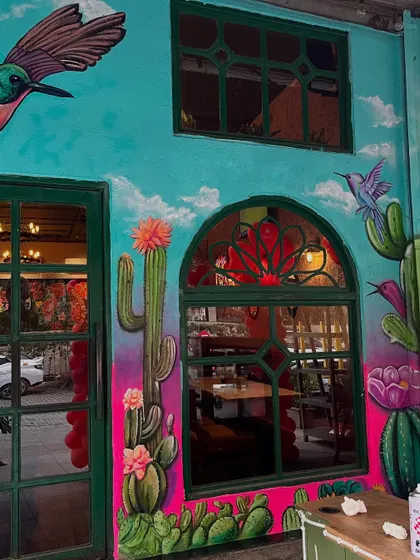 The restaurant facade with its new vibrant mural, showing how the artwork frames the windows and door.