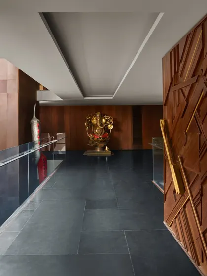 The entrance to the Baid Residence features a grand Ganesha sculpture by Narayan Sinha, set against a backdrop of bronze and wood paneling. The salvaged wood door with its intricate carving provides a powerful first impression.