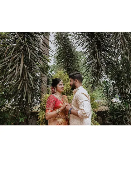 A couple stands amidst palm trees, a classic Kerala backdrop for their wedding portraits.