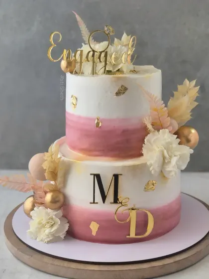 A two-tiered engagement cake in soft wine tones. This 3kg Cherry Chocolate cake is adorned with edible gold leaf and fresh flowers.