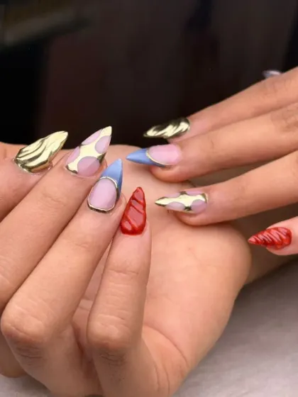 An eclectic and artistic set combining different shapes and 3D textures, including chrome-gold tips and a swirled red accent nail. This is for the client who wants truly unique nails.