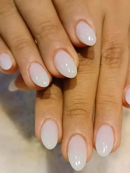A beautiful "milky white" manicure on oval-shaped nails, offering a soft, clean, and modern alternative to a stark white.