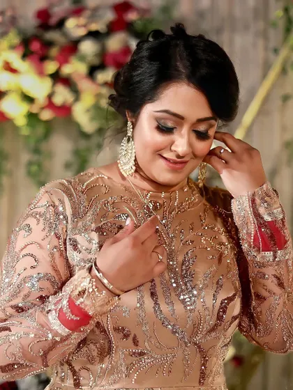 A stunning reception look featuring a classic updo and glamorous makeup with defined eyes. The client looks radiant and elegant in her heavily embellished gown.