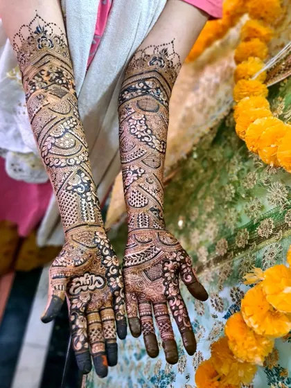 An intricate bridal design with personalized Arabic calligraphy on the palm, surrounded by floral and geometric patterns.