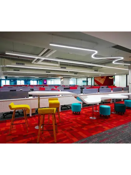 Another angle of the collaborative zone at Mindsprint, highlighting the use of bright red patterned carpeting and varied seating. This design choice helps to demarcate different functional areas within the larger open-plan office.