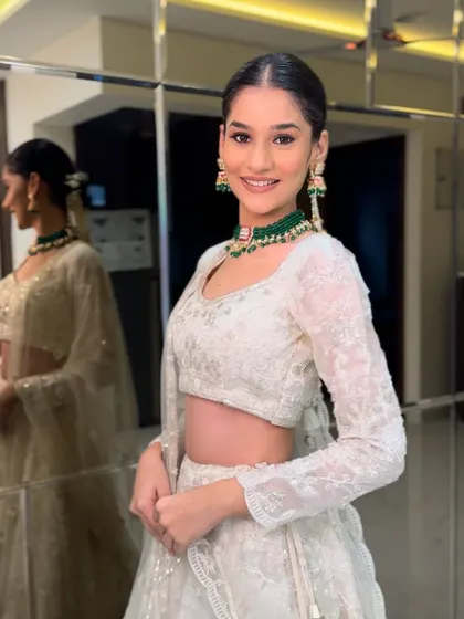 A vision in white. This bride is the picture of elegance with a clean, fresh makeup look, a sleek bun, and a pop of color from her emerald jewelry.