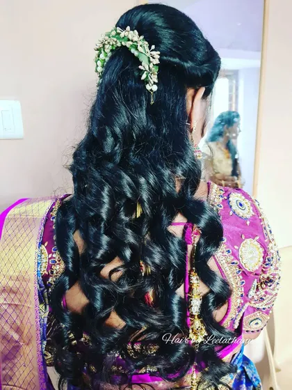 A modern take on event hairstyling. This look features soft, voluminous curls and a delicate floral hair accessory, perfect for a reception or engagement.