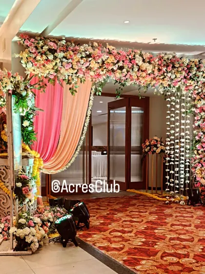 A lush and grand floral entrance arch at Acres Club. The combination of pink and white flowers with hanging floral strings creates a beautiful and welcoming entryway for a wedding.