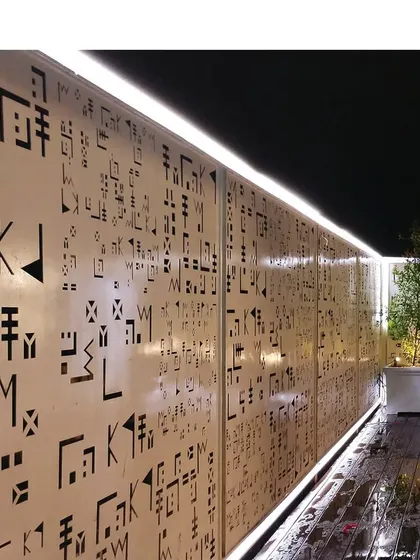 A detail of a custom-designed perforated screen on a modern facade. This element provides privacy and sun shading while creating intricate light patterns, adding a layer of artistry to the building.