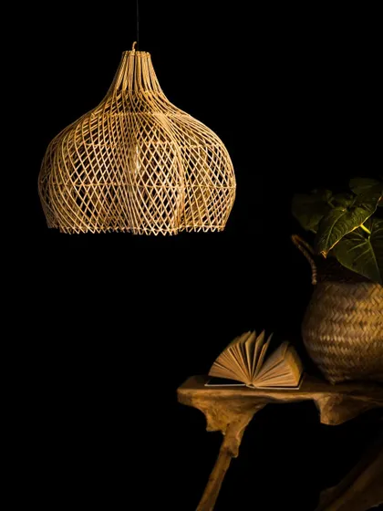 This elegant globe-shaped rattan lamp is pictured here unlit, set beside a book to suggest its use in a quiet reading corner. Its design is simple, yet sophisticated.