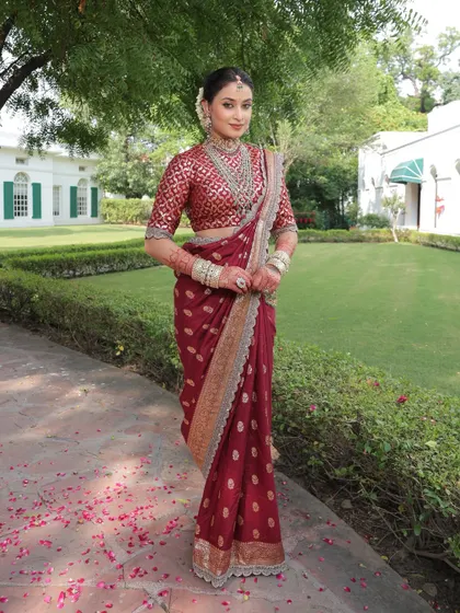 An example of timeless elegance. This bride's look is built around a beautiful maroon saree, enhanced with soft, natural makeup and a traditional hair bun, perfect for a classic wedding ceremony.