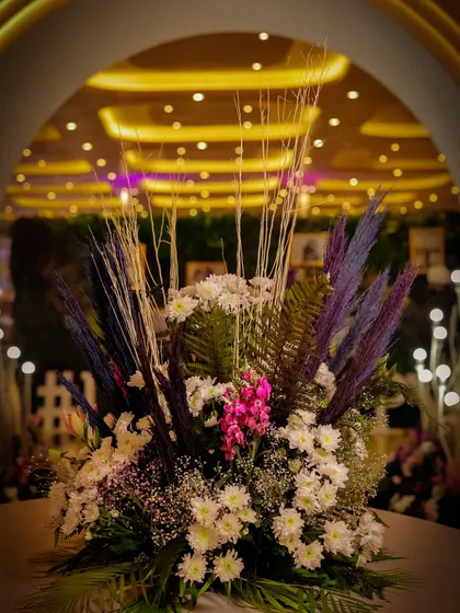 A beautiful floral arrangement with a mix of fresh and dried elements, placed to welcome guests. The backdrop of warm, ambient lighting creates an inviting entryway.