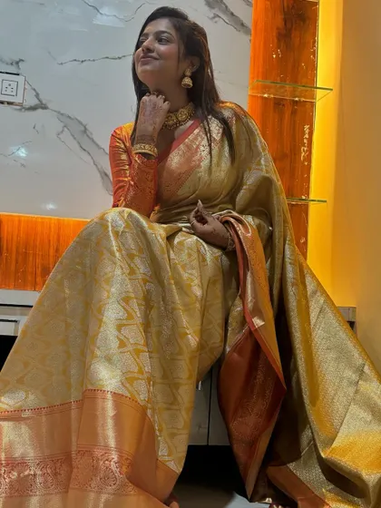 Sonu looking thoughtful and elegant, seated against a modern marble wall.