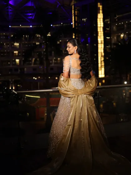 A full back view of the bride against the city lights, showcasing her dramatic gown and elegant hairstyle.