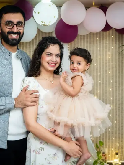 A lovely family portrait from a first birthday celebration at home. The simple balloon and fairy light backdrop creates a warm and festive atmosphere for this special milestone.