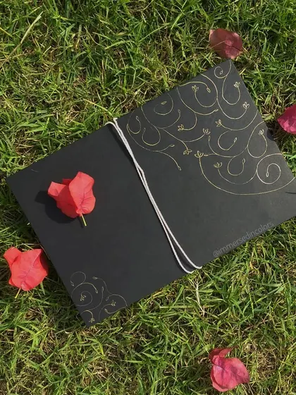 The full presentation of a commissioned letter. The piece is written in gold on black paper, detailed with blind debossed flourishes, and enclosed in a handmade envelope, ready for gifting.