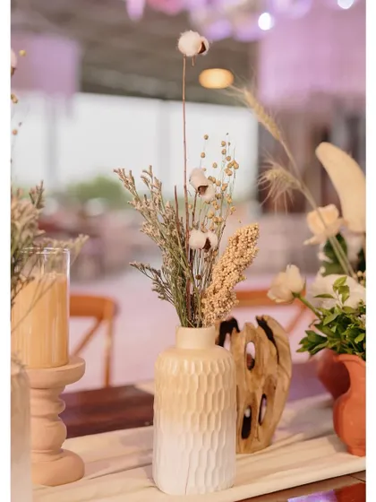 A close-up of the dried floral arrangement in a textured vase.