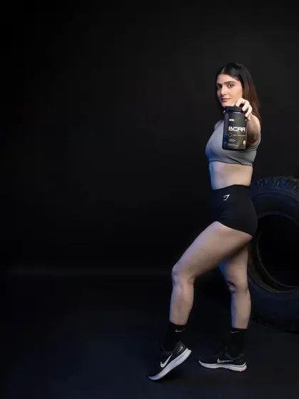 A female model holding a BCAA supplement out towards the viewer, creating an engaging and direct call to action.