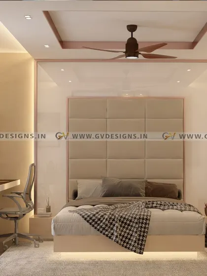 This modern bedroom design is a sanctuary of calmness and style. It features a large cushioned headboard, a lacquered glass back panel with copper-colored trim, and a dedicated study desk, all tied together with warm ambient lighting.