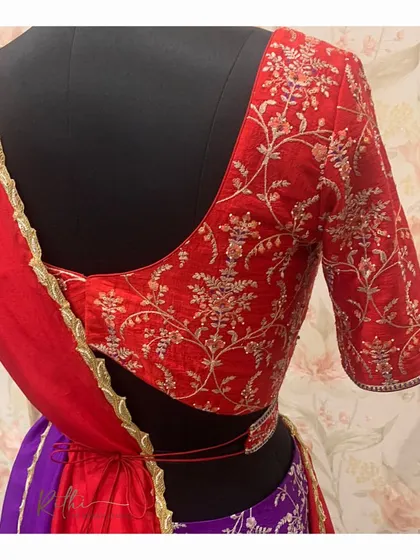A view of the back of the red embroidered blouse, showing the intricate floral design.