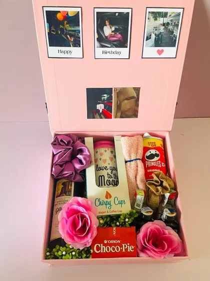 The hamper includes mini liquor bottles, snacks, a travel cup, and other fun items, all beautifully arranged in the pink box.