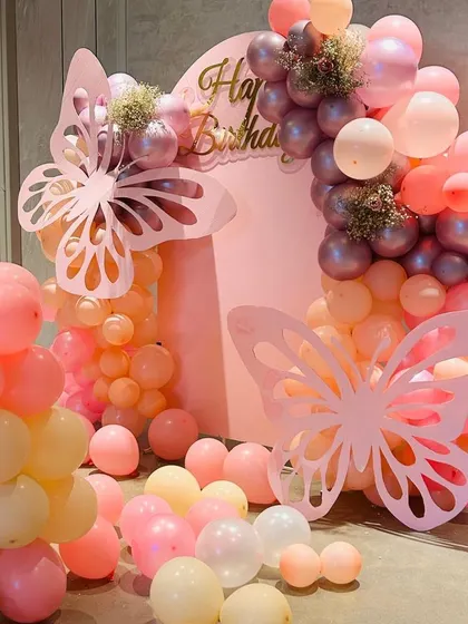 This angle highlights the flow of the balloon decor and the placement of the butterfly props. We use balloons of different sizes and finishes to create texture and visual interest.