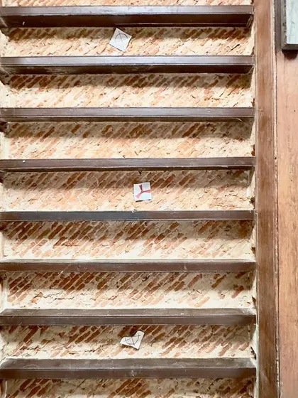 A detail of exposed brickwork behind wooden louvers. This image reveals the hidden layers of construction, showing how different materials were combined in the original building.