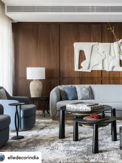 A wide view of the living space, showing the interplay between the dark wood paneling, the soft blue sofas, and the various curated art and decor pieces. The design ensures the sprawling house is usable and functional without appearing stark.