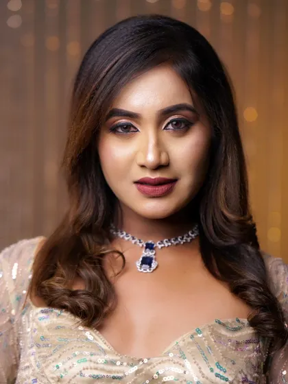 A confident portrait showing a modern makeup look. The eyes are defined with a soft wing, and the lips are a deep, sophisticated shade.